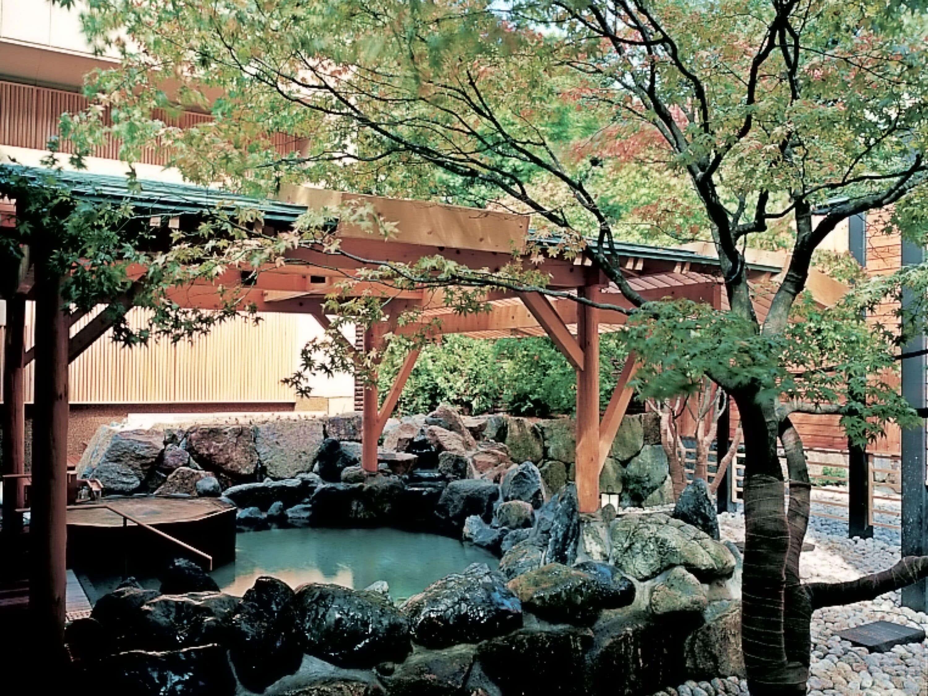 A traditional Japanese garden with a koi pond, wooden bridge, and stone lanterns.