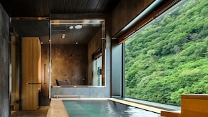 Un spa moderno con un banco de madera, un pequeño rincón de descanso y vistas a un bosque verde y frondoso.