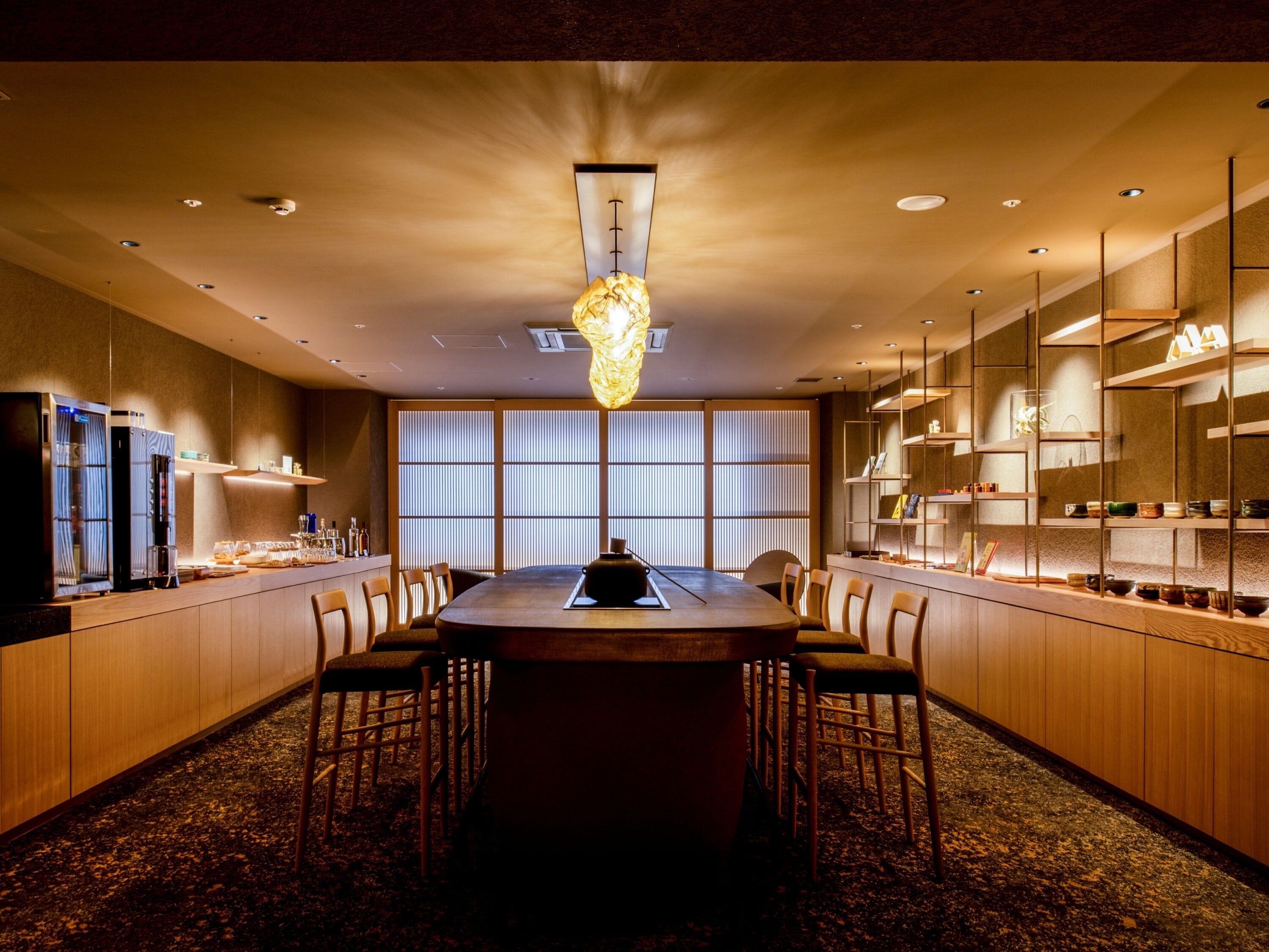 A modern dining area with a central table, chairs, and a unique chandelier.