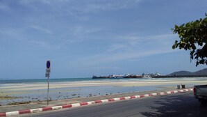 A coastal road with a no parking sign, a beach, and a pier in the background. - Jinta City Samui (Koh Samui)