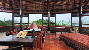 A room with a wooden ceiling, large windows, a bed, a table with a lamp, and chairs. - Binh An Village Vung Tau (Ho Chi Minh City)