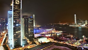 A nighttime cityscape with illuminated skyscrapers and a waterfront area. - Crafa Harbour Hotel (Hong Kong)