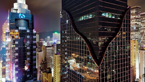 A cityscape with modern high-rise buildings, one featuring a distinctive curved glass facade. - Crafa Harbour Hotel (Hong Kong)