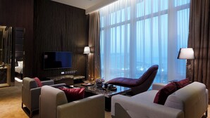 A modern hotel room with a large window, a flat-screen TV, a marble coffee table, and two armchairs. - Crafa Harbour Hotel (Hong Kong)