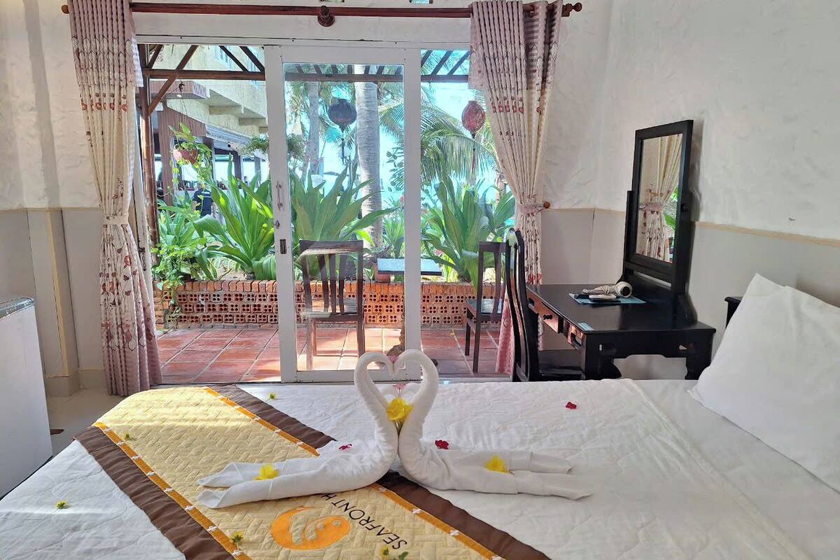 A hotel room with a bed, a desk, and a view of a garden.