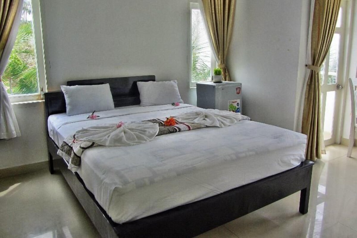 A bedroom with a bed, curtains, a nightstand, and a window.