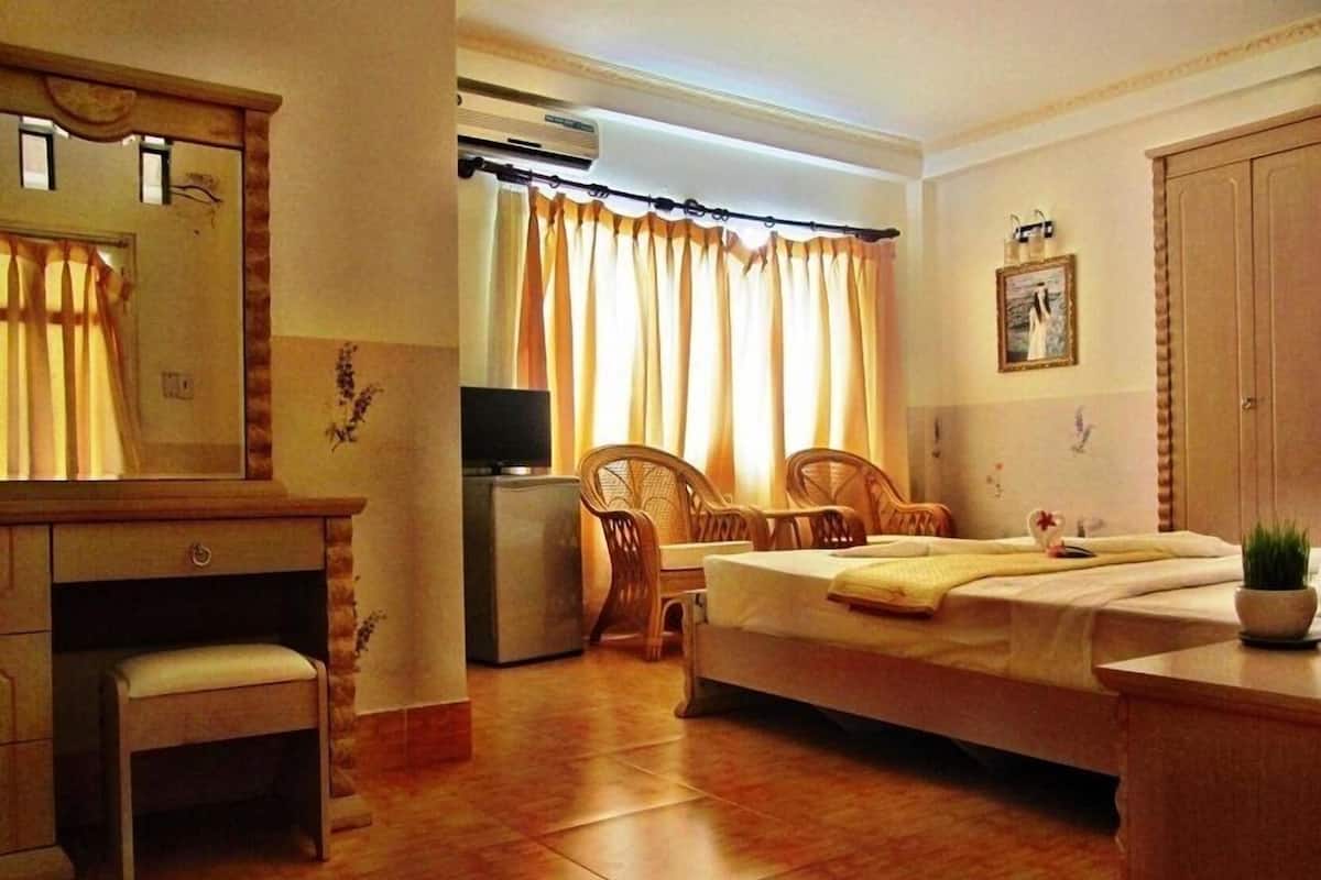 A hotel room with a bed, a desk, a chair, a television, and a wardrobe.