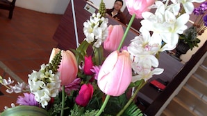 Balcão de recepção com arranjo floral em primeiro plano.