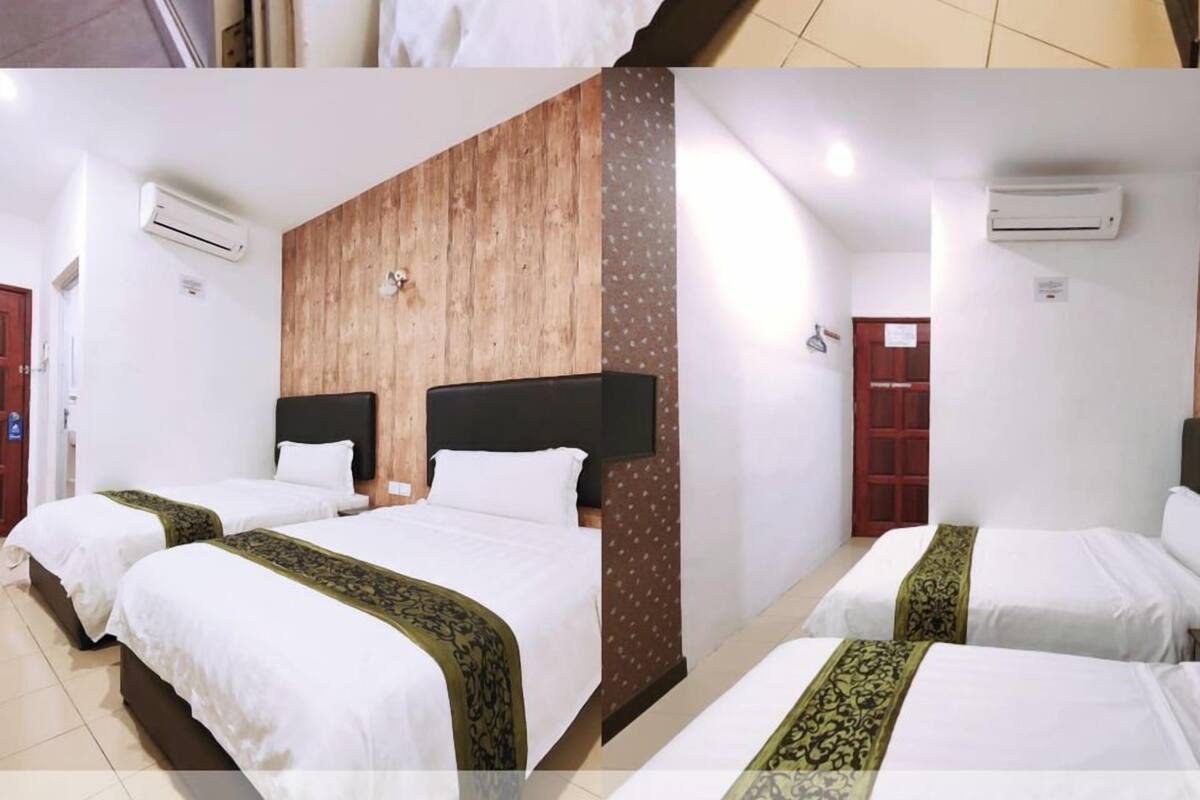 A hotel room with two beds, a wooden accent wall, a framed picture, and an air conditioning unit.