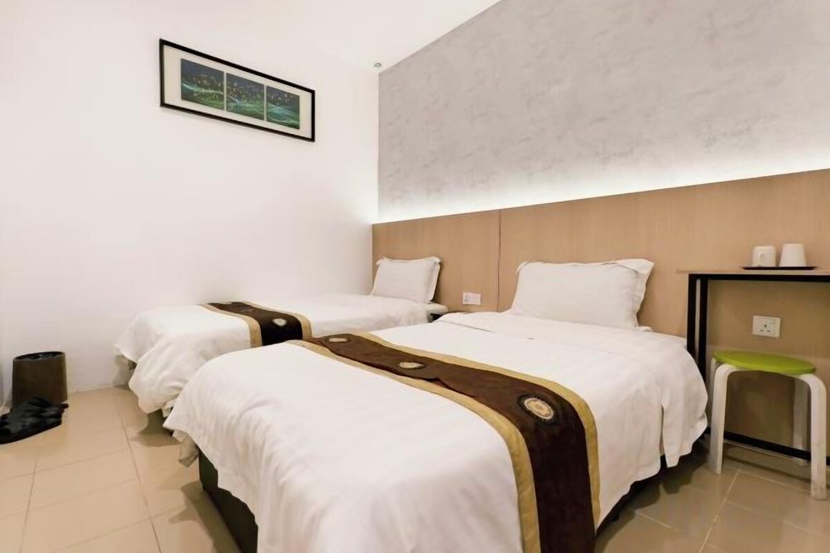 Habitación de hotel con dos camas, una mesita de noche, una silla y estante en la pared.