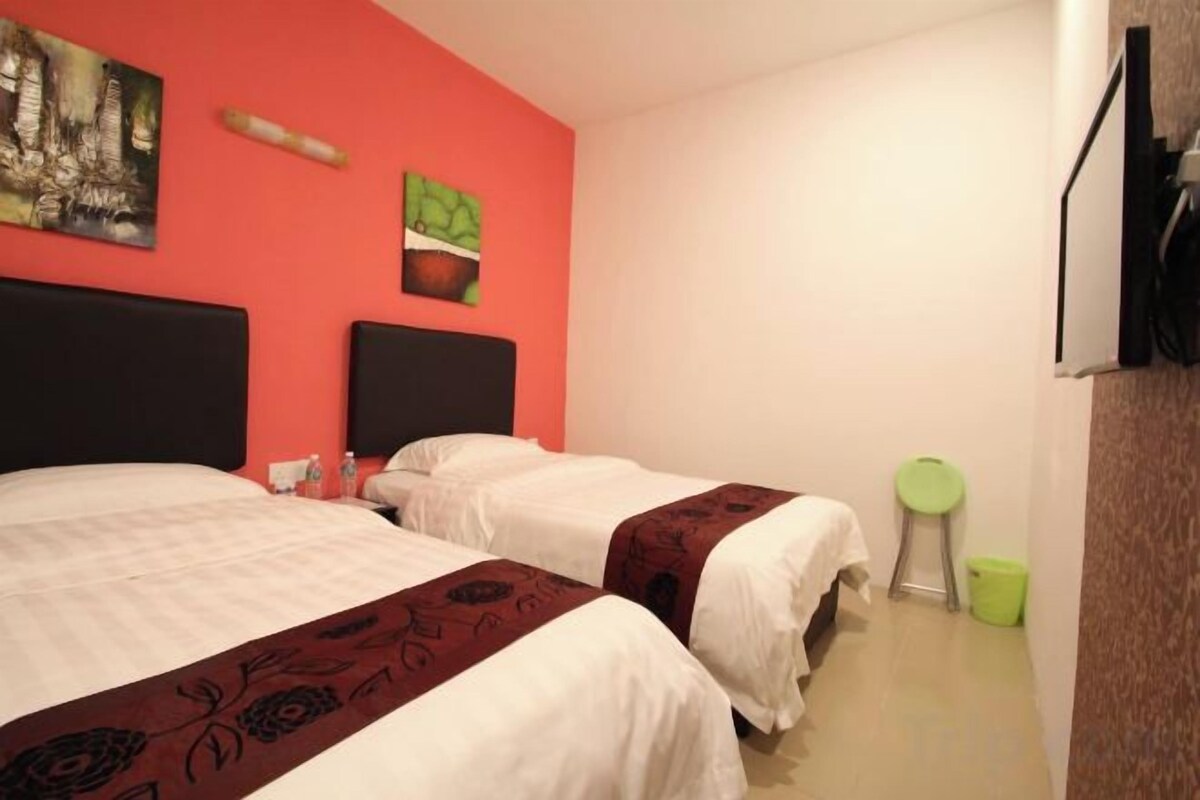 Habitación de hotel con dos camas, una pared roja y un bote de basura verde.
