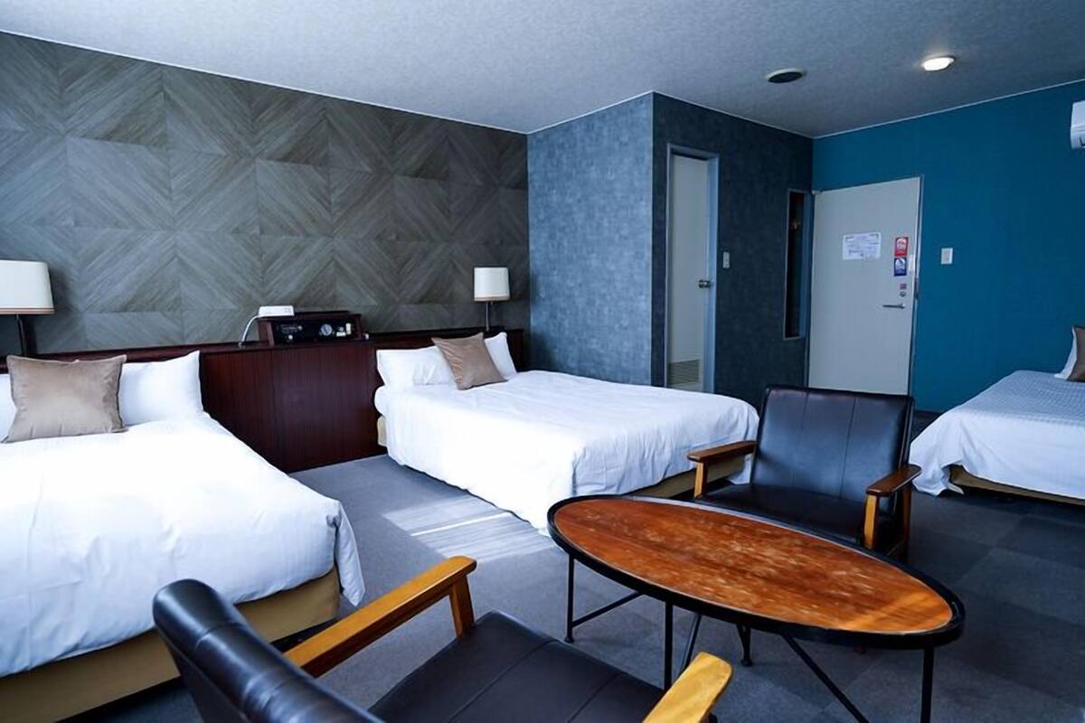 Ein Hotelzimmer mit zwei Betten, einem Schreibtisch, einem Stuhl und einem kleinen Tisch.