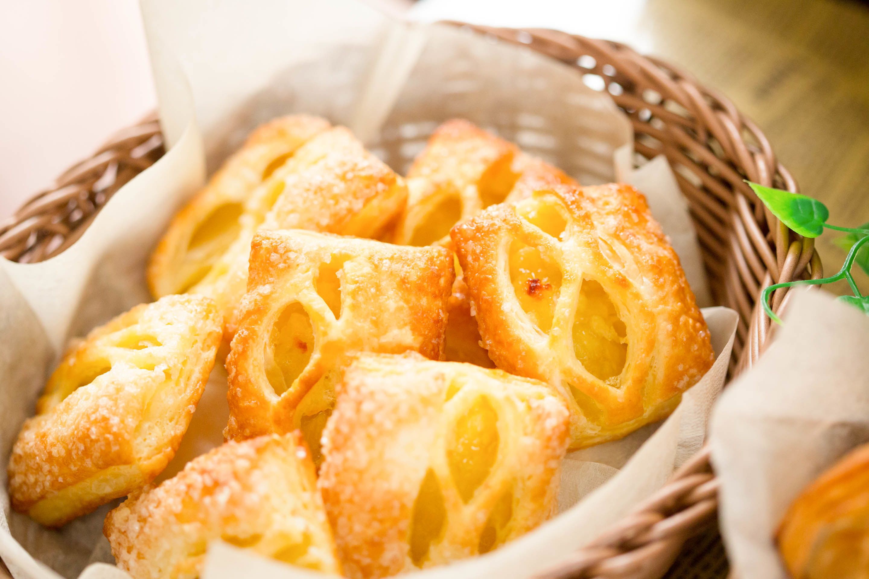 A basket of golden-brown pastries with a sugar coating, placed in a woven basket.