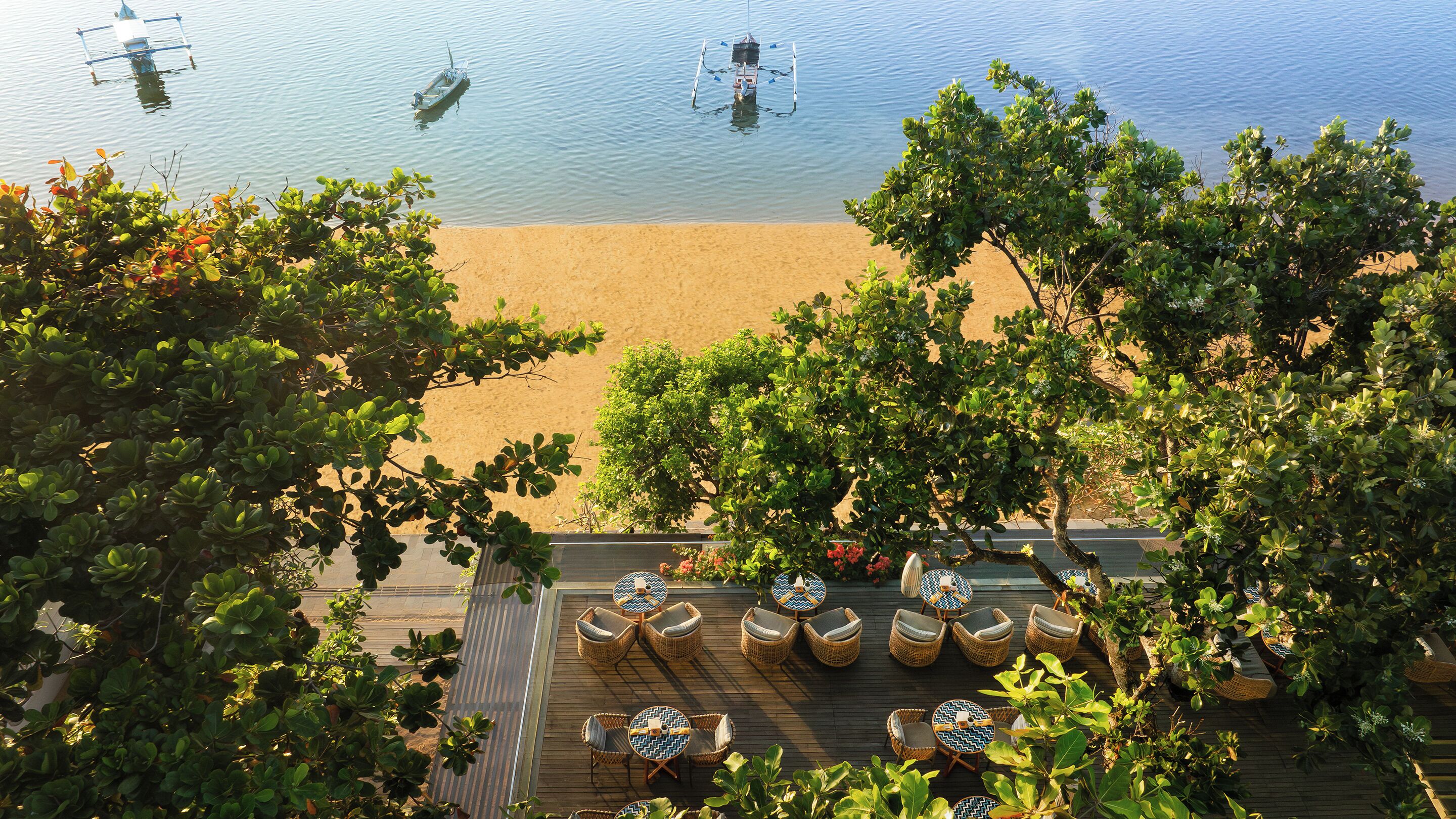 A beachside patio with wicker furniture and a view of the sea.