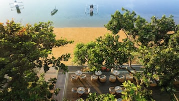 A beachside patio with wicker furniture and a view of the sea.
