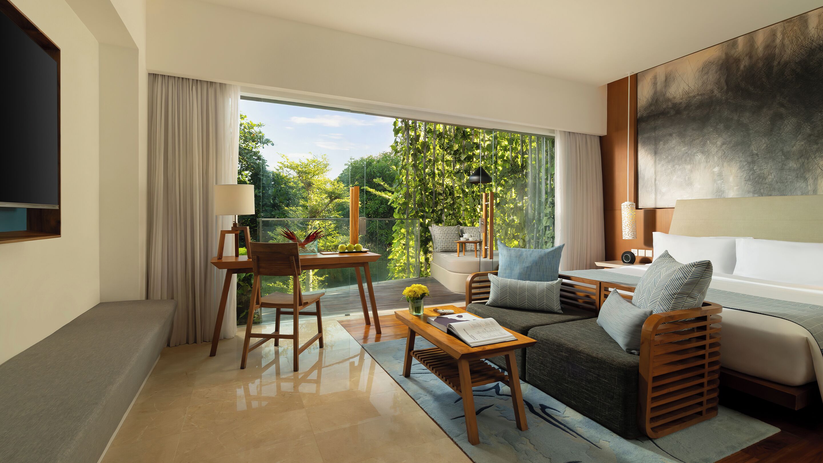 A modern hotel room with a balcony, a sofa, a dining table, and a TV.