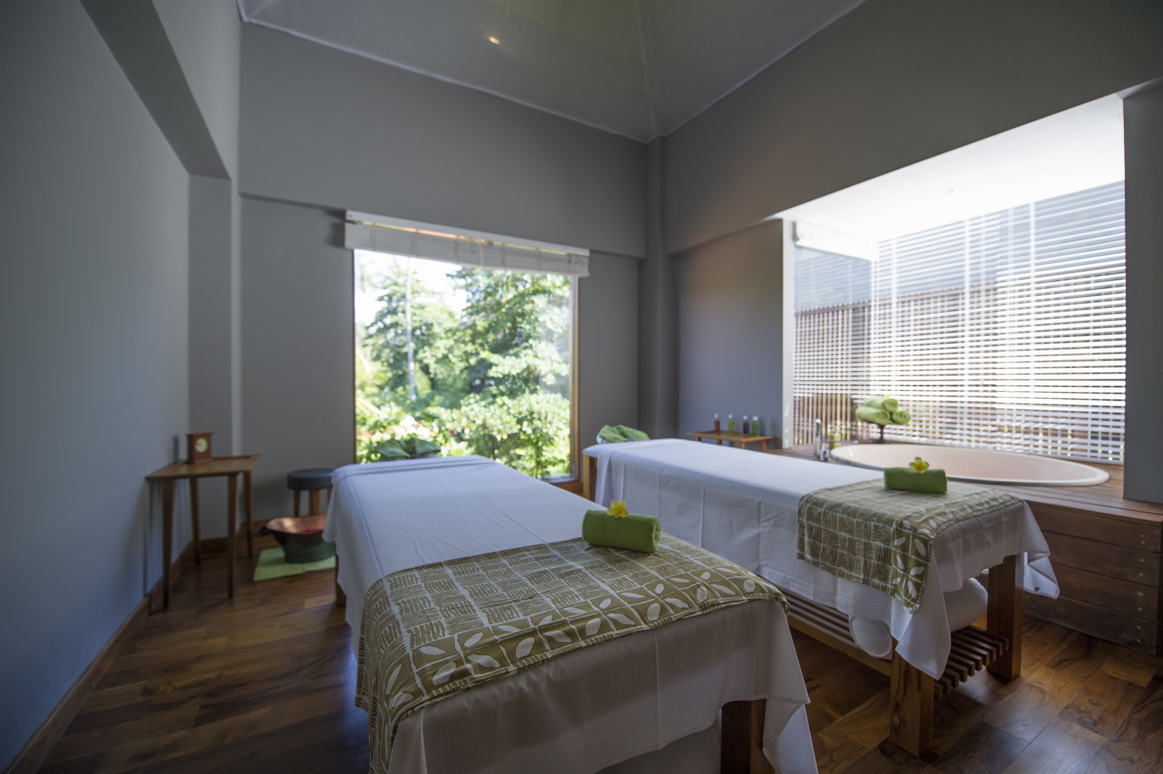 A room with two beds, a large window, and a sink.