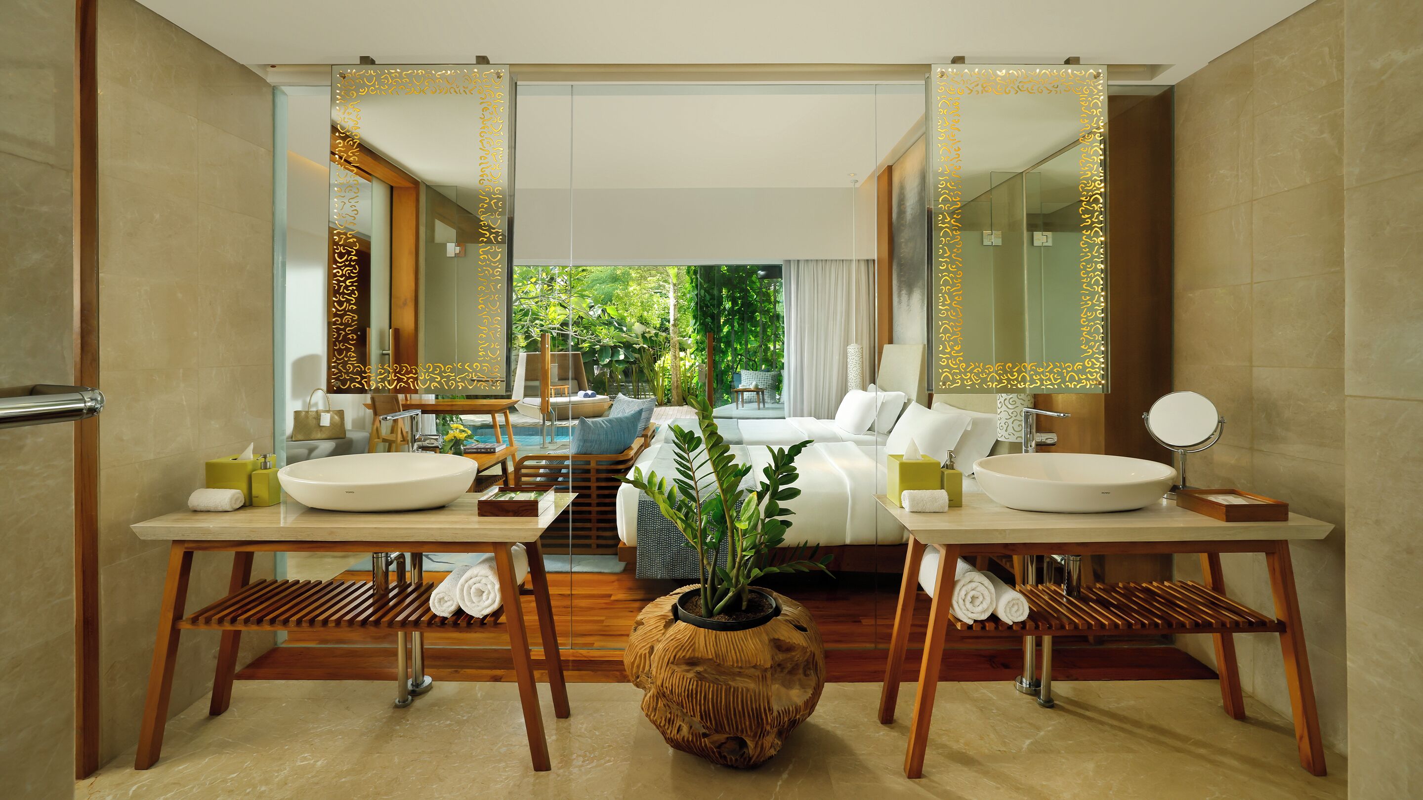 Ein modernes Badezimmer mit zwei Waschbecken, einem großen Spiegel und Blick auf ein Schlafzimmer mit Bett und Fenster.