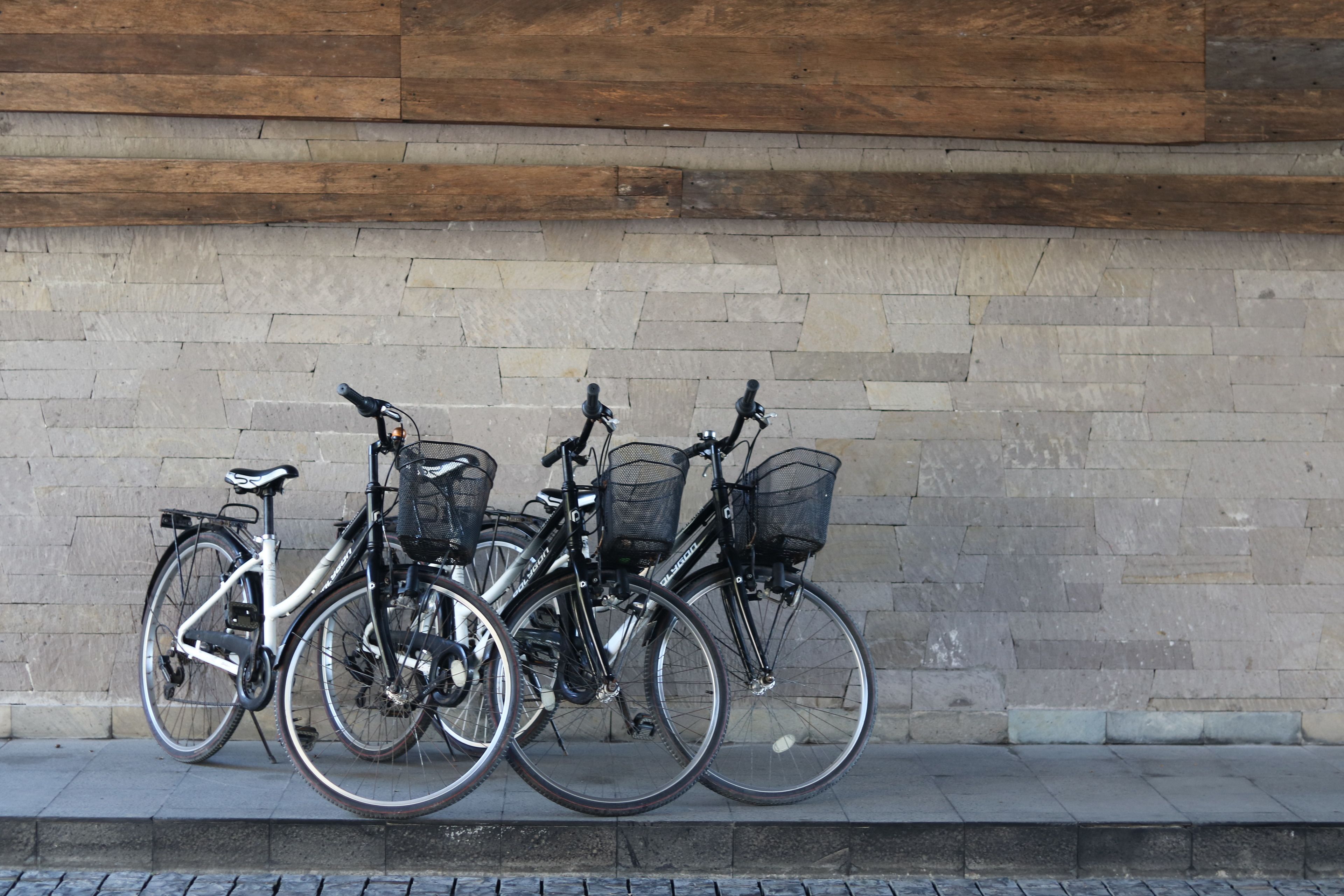 Three bicycles parked against a stone wall.