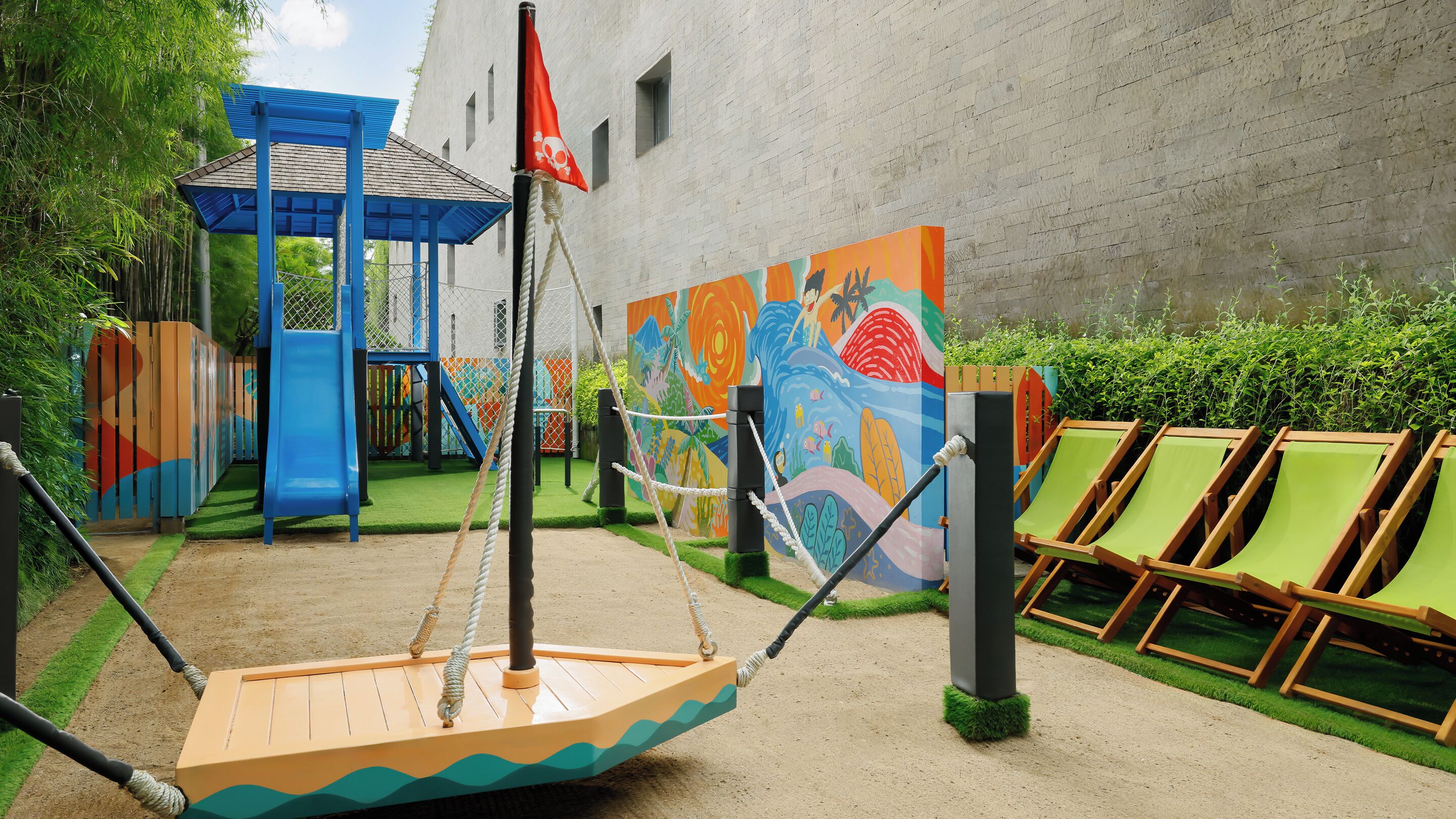 A playground with a swing set, a slide, and a mural.