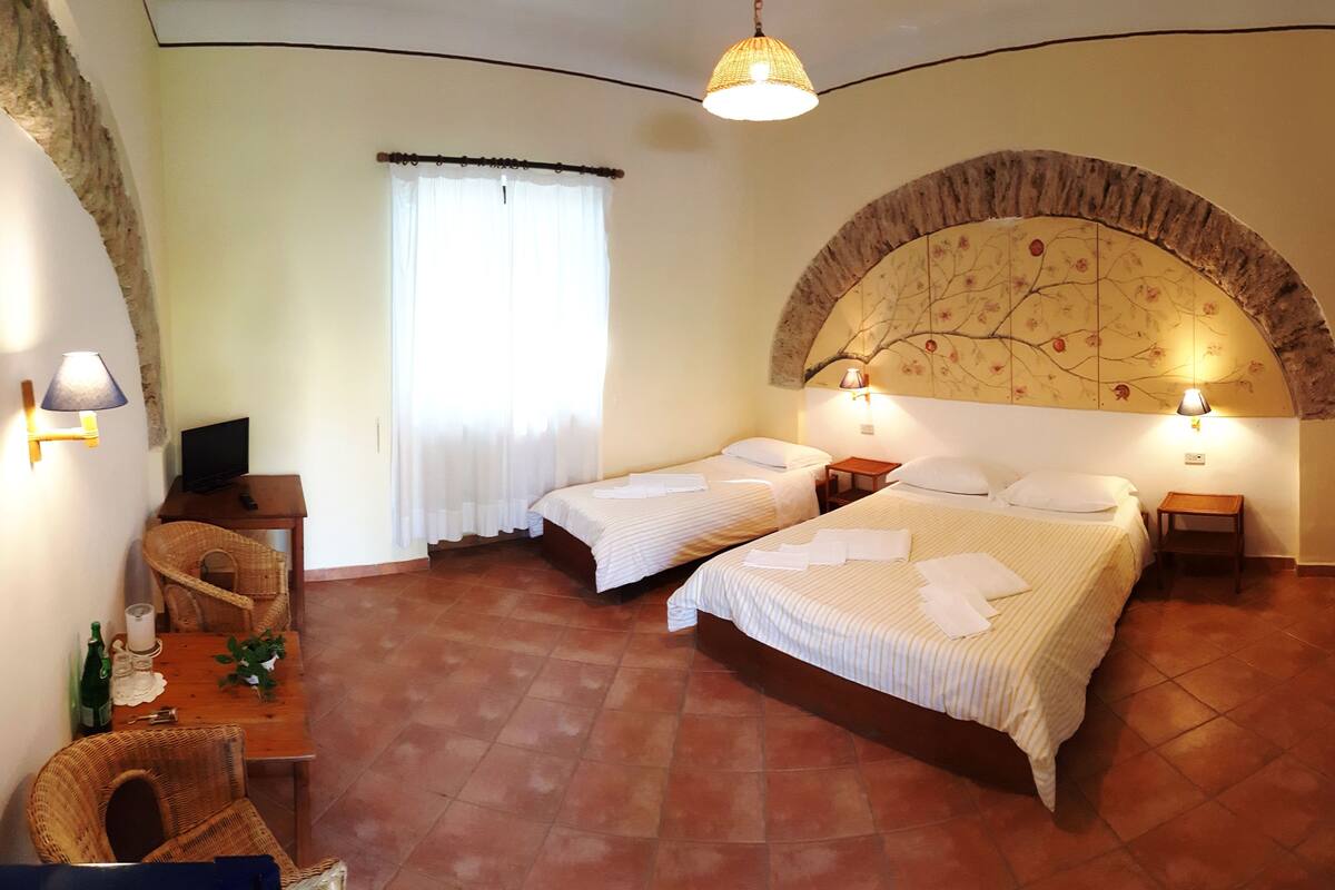 Une chambre d’hôtel avec deux lits, un bureau avec un ordinateur, une chaise et un mur décoratif.