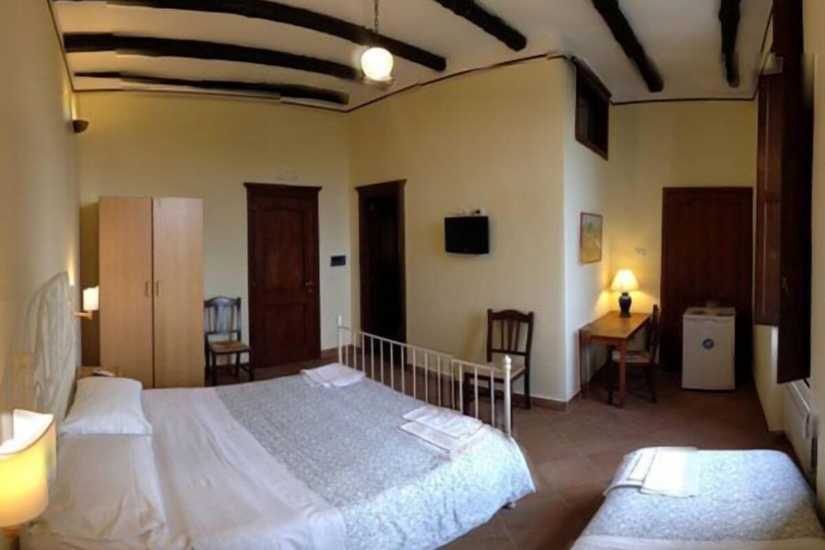 Une chambre avec deux lits, un bureau, une chaise, une télévision et une armoire.