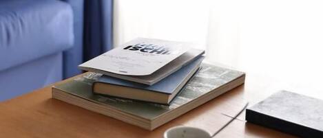 Un tavolino con una tazza di caffè, una pila di libri e un portatile.