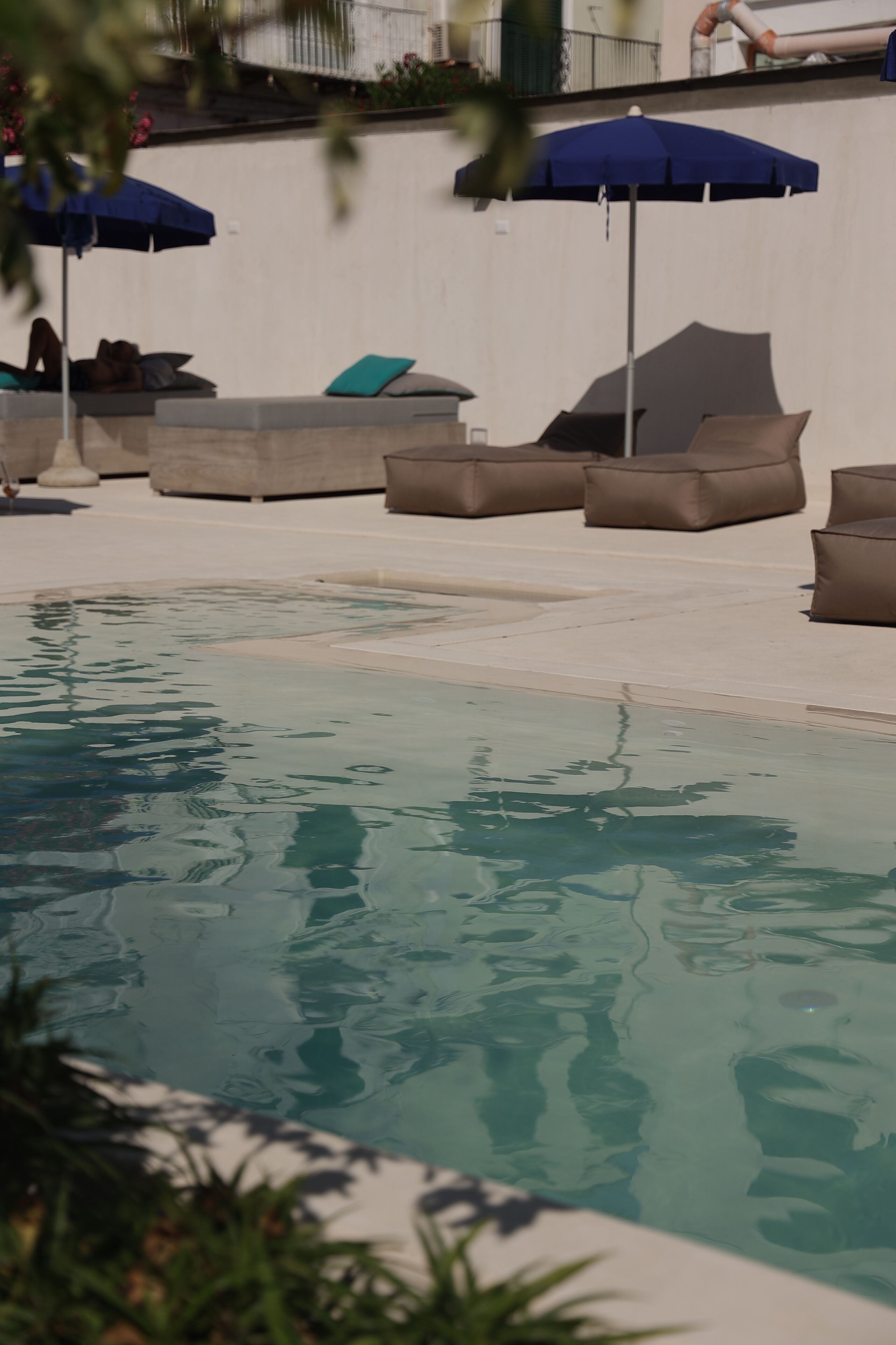 A swimming pool with lounge chairs and umbrellas.