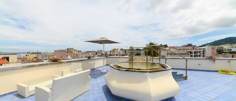Terraza en la azotea con jacuzzi, mobiliario exterior y vistas a la ciudad.