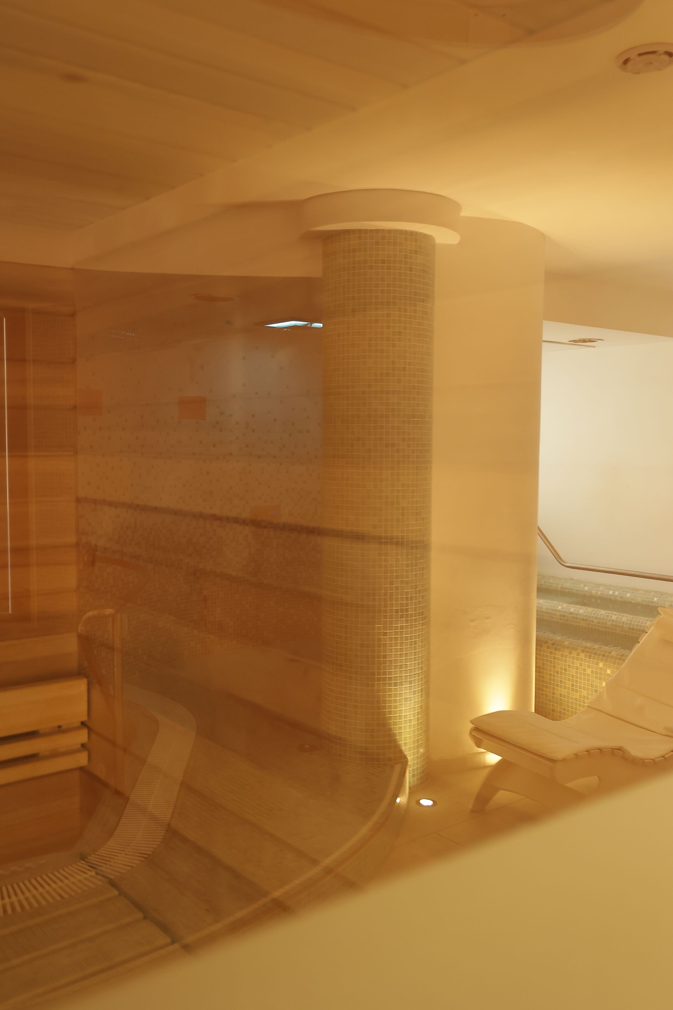 A spa area with a tiled wall, a wooden bench, and a small table.