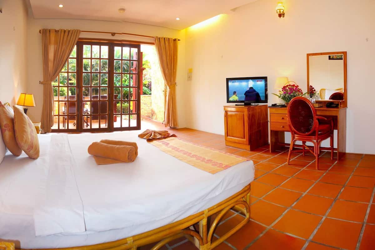 A hotel room with a bed, a desk, a chair, a television, and a window with curtains.