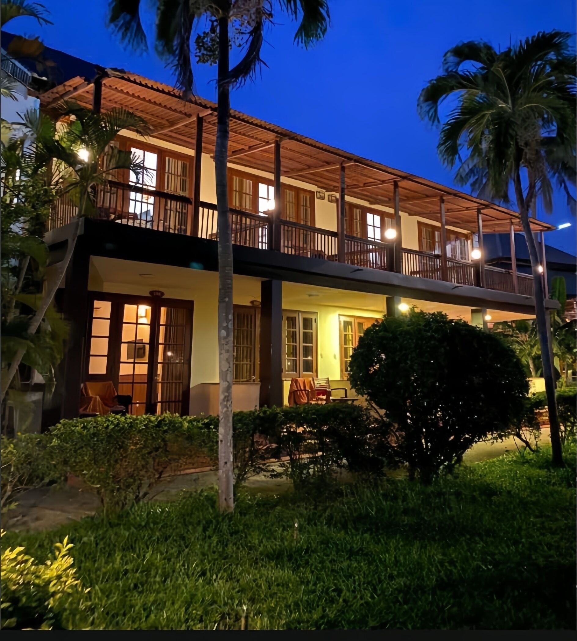 A two-story building with a balcony, a covered outdoor seating area, and a well-maintained garden.