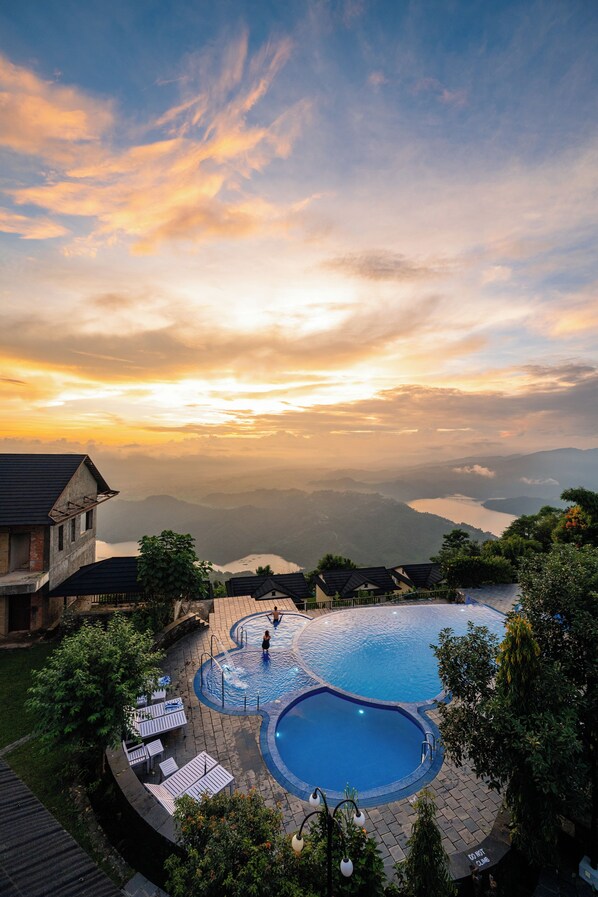 A swimming pool with a view of mountains and a sunset. - Rupakot Resort (Lekhnath)