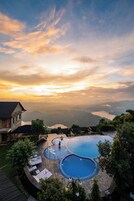 Una piscina con vista a montañas y un atardecer.