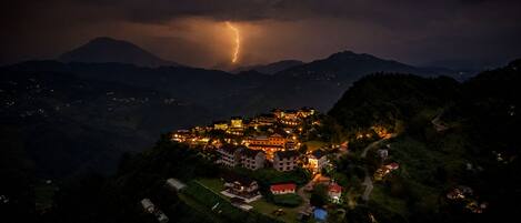 A mountainous town at night with a lightning strike.