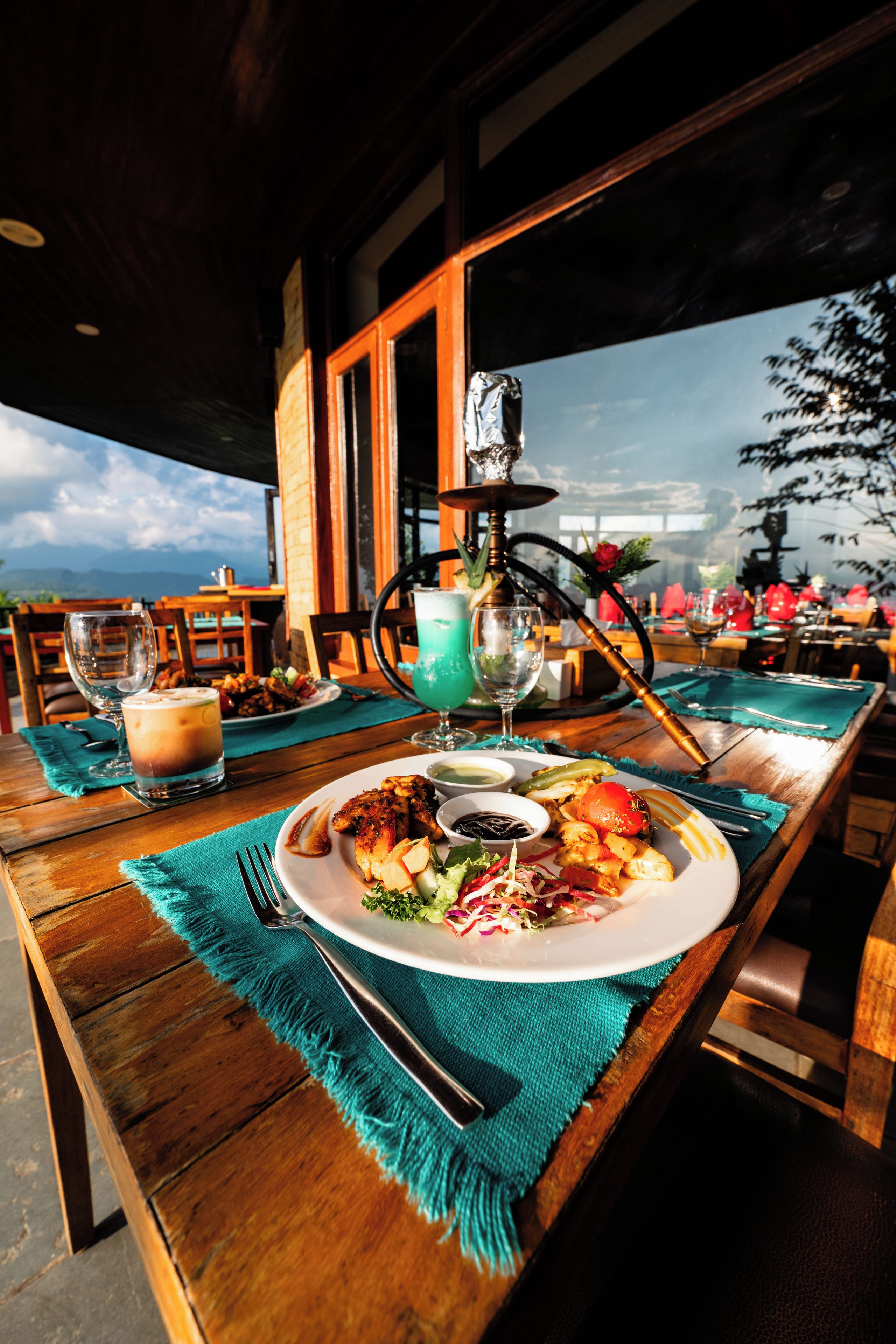 A dining table with a plate of food, a hookah, and drinks.