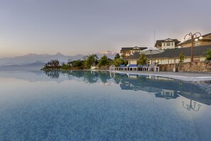 A clear view of a swimming pool with a mountain backdrop, reflecting nearby buildings and trees.