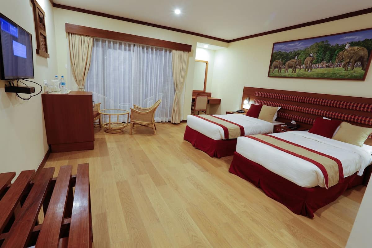 A hotel room with two beds, a desk, a chair, a TV, and a painting on the wall.