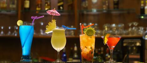 A bar with four different cocktails, each with unique garnishes and straws.