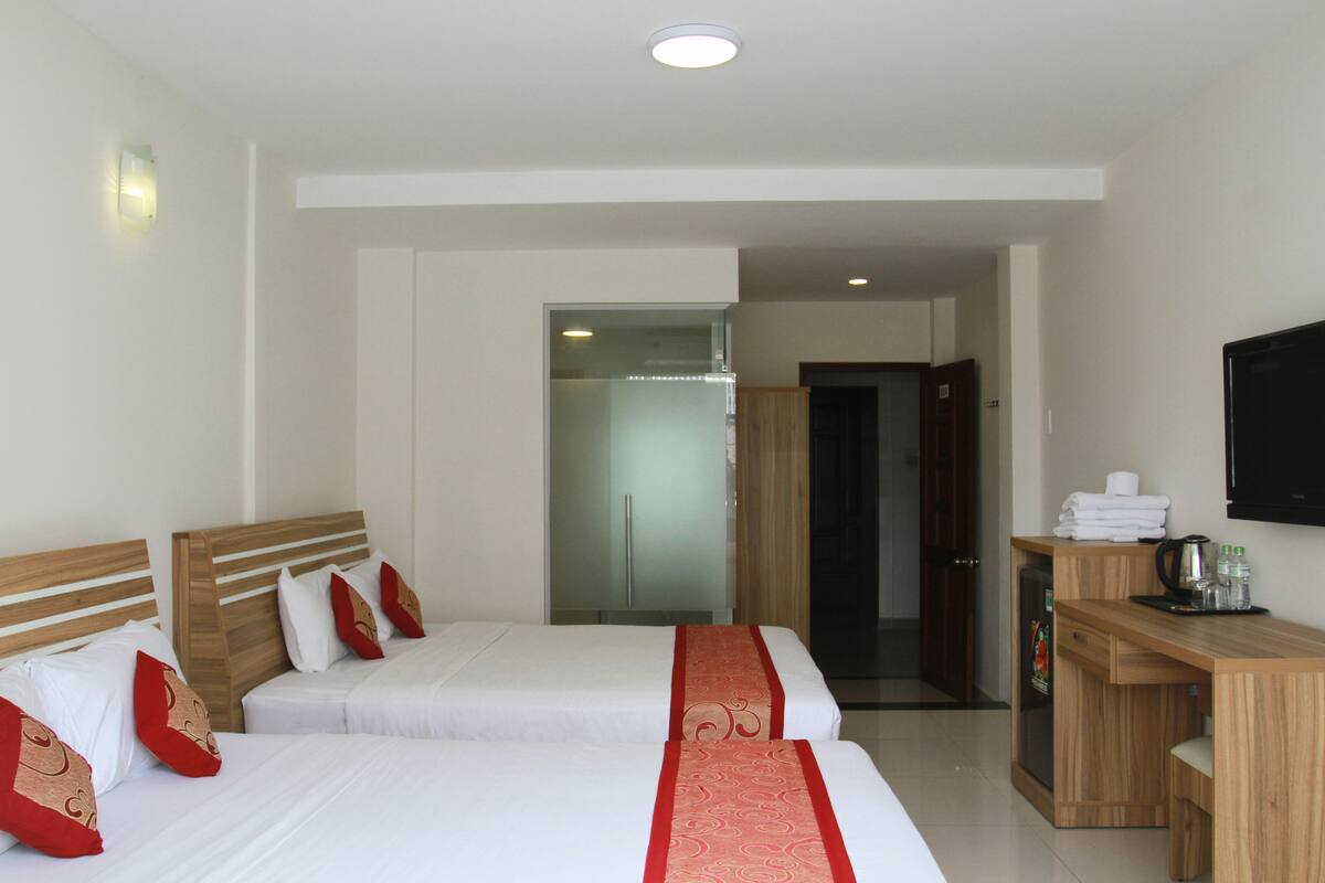 A hotel room with two beds, a desk, a television, and a door leading to a bathroom.