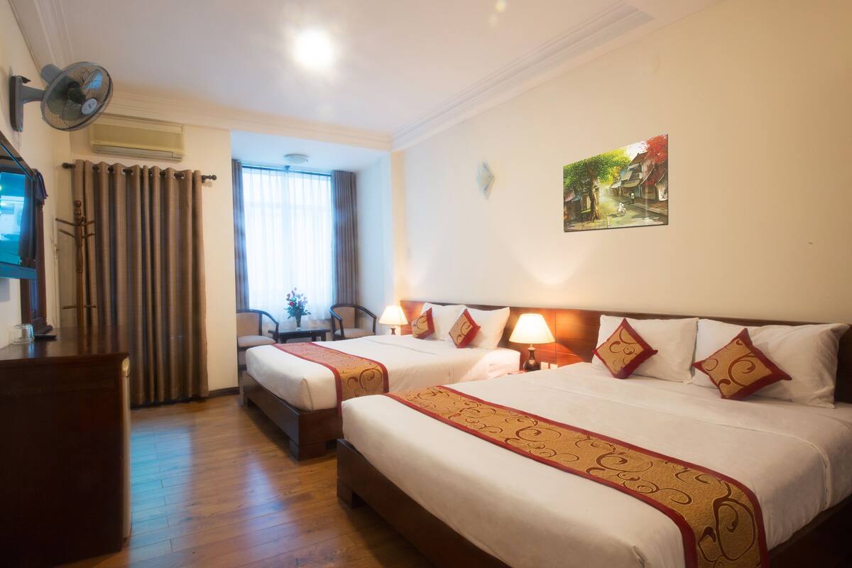 A hotel room with two beds, a desk, and a chair.