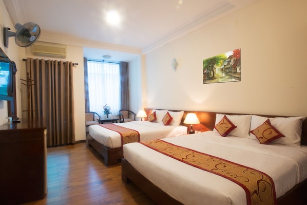 A hotel room with two beds, a desk, and a chair.