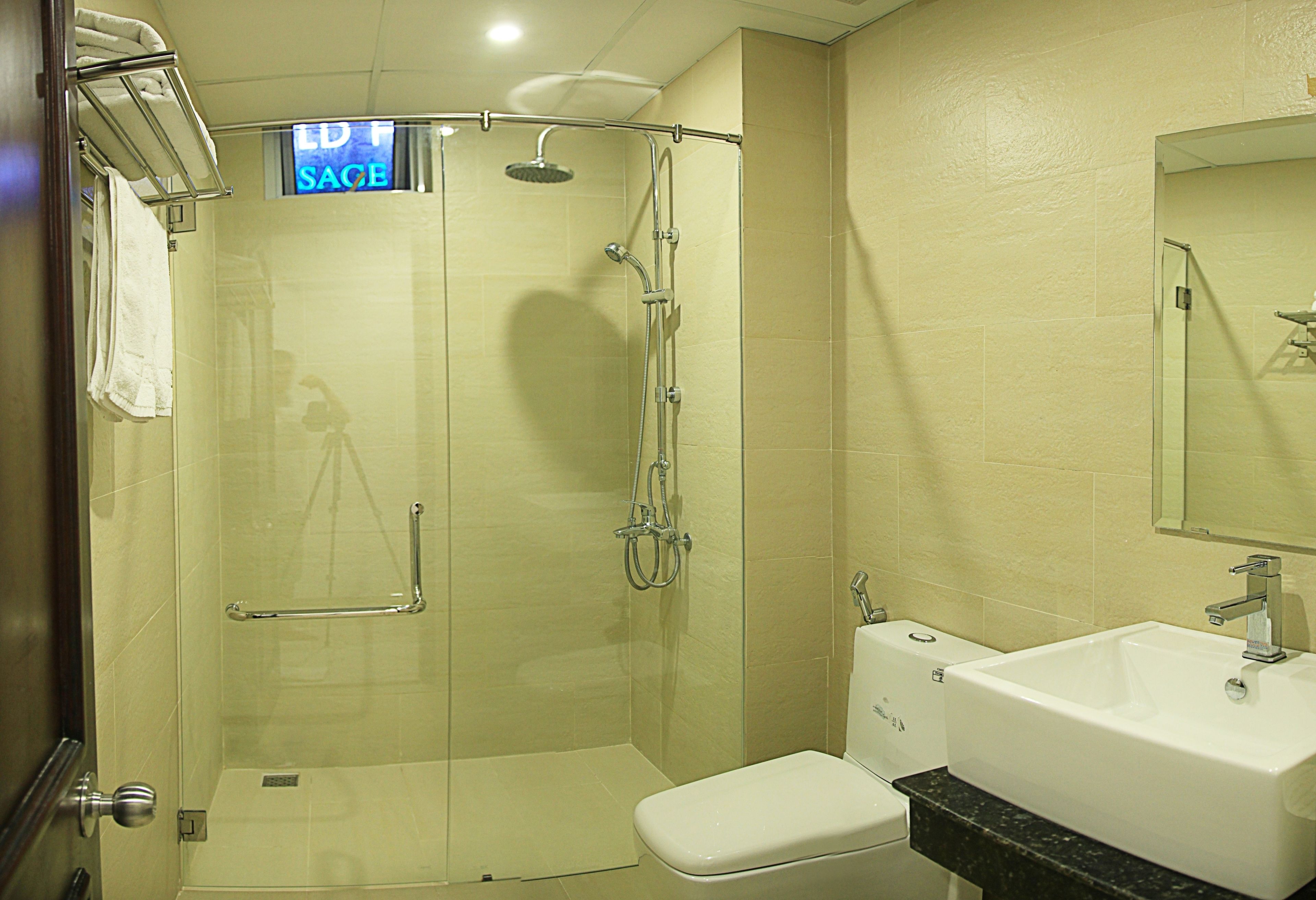 A modern bathroom with a glass-enclosed shower, a white toilet, and a sink with a black countertop.