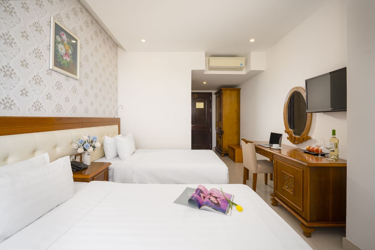 A hotel room with two beds, a desk, a television, and a mirror.