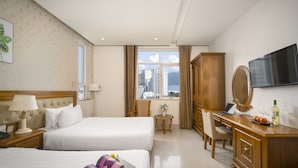 A hotel room with two beds, a desk, a TV, and a view of the city. - Royal Family Hotel Da Nang (Da Nang)