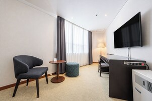 Una habitación de hotel con una cama, un escritorio, una silla, un televisor y una lámpara.