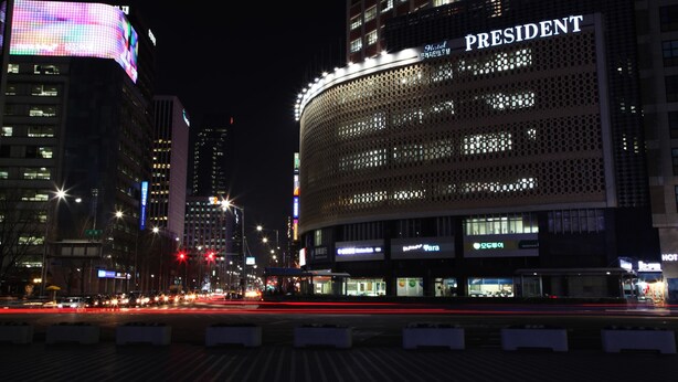 A hotel with a prominent 'PRESIDENT' sign, modern architecture, and a busy street with light trails. - Hotel President (Seoul)