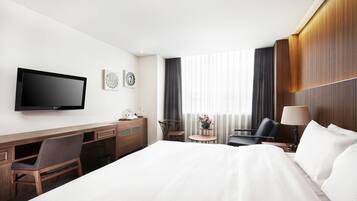 Une chambre d’hôtel équipée d’un lit, d’un bureau, d’une chaise, d’une télévision et d’une petite table avec une lampe.