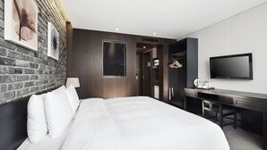 A modern hotel room with a large bed, a desk, a TV, and a brick wall. - Hotel President (Seoul)