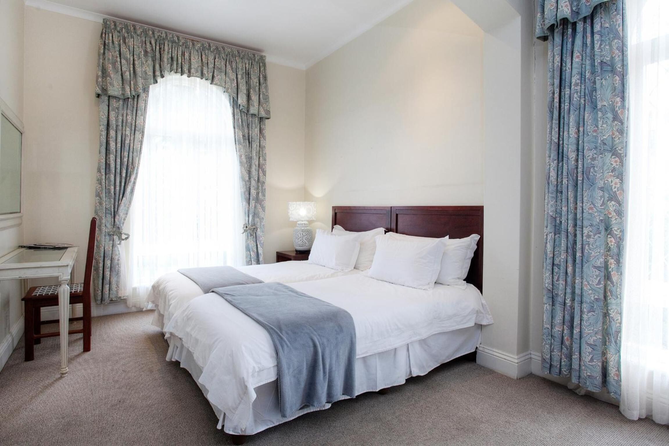 A hotel room with a large bed, a desk, and a chair.